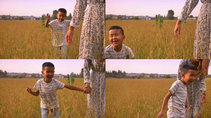 令人敬畏的亚洲孩子在黄色田野的乡村里快乐地跑在母亲附近