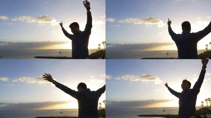 男子在欢乐和加那利群岛海洋日落全景中举起武器
