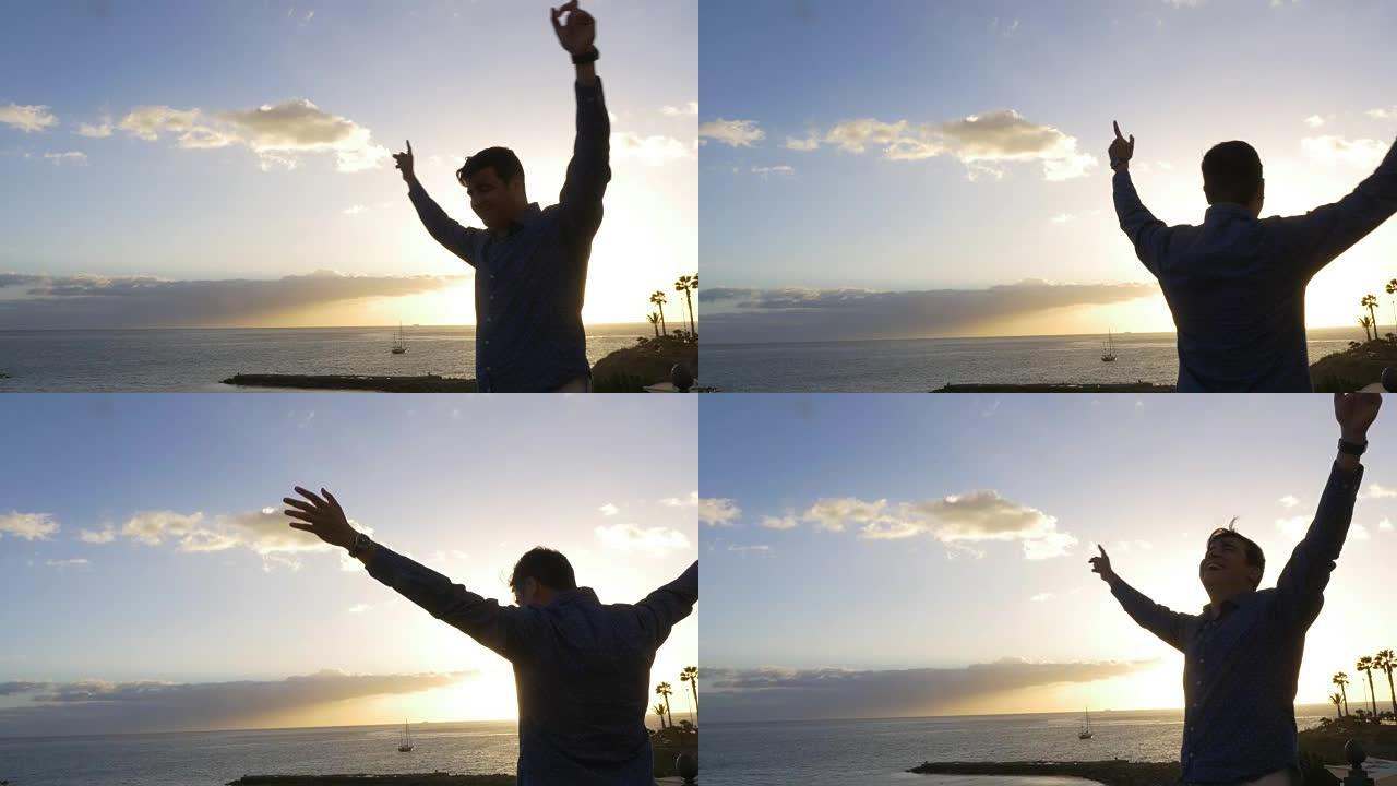 男子在欢乐和加那利群岛海洋日落全景中举起武器