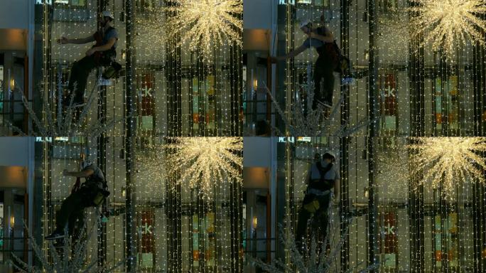 工业登山者在购物中心的无支撑空间中安装圣诞节装饰品