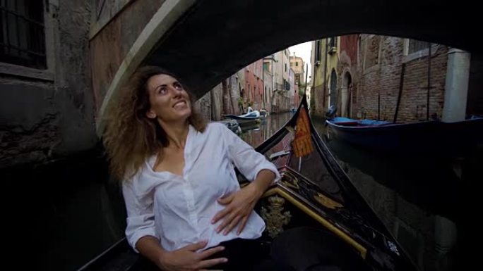 乘坐缆车的年轻女子在威尼斯的一座桥下航行
