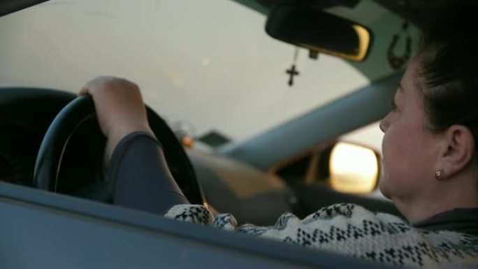 一名妇女驾驶着一辆车，从后视镜中可以看到山景