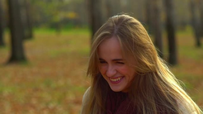 年轻迷人的女孩在秋季公园大笑。