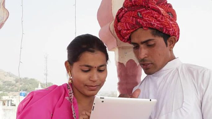 在印度拉贾斯坦邦，一对迷人的印度夫妇在平板电脑上学习和教学