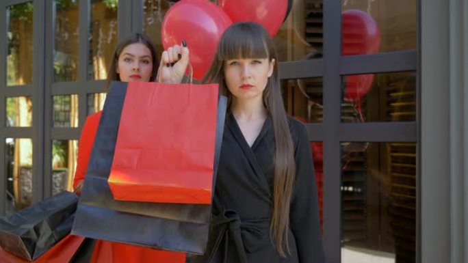 黑色星期五，严肃女孩的肖像在黑暗背景上展示了很多纸袋，在女友面前购买了气球