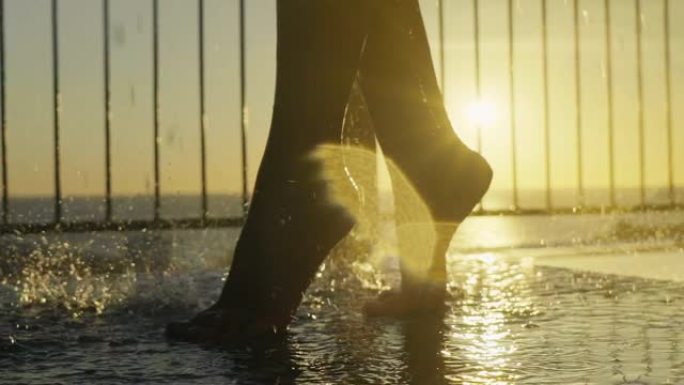 淋浴时性感女人腿的特写镜头。日落时的热带户外淋浴。