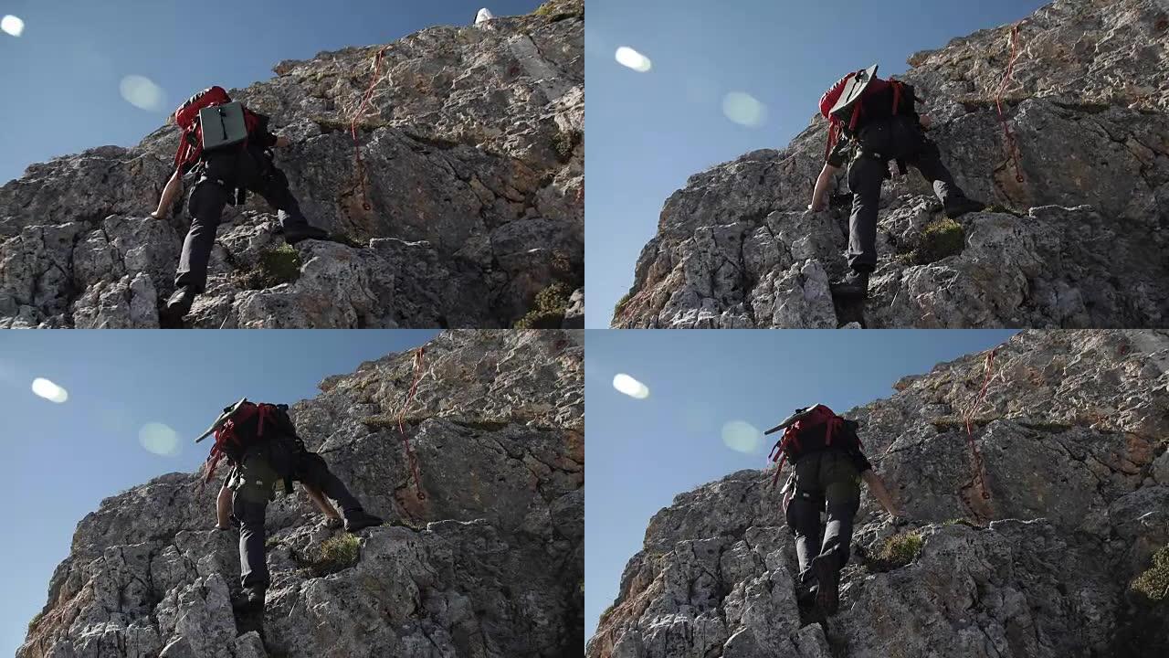 一个戴着帽子的人在山上系着绳子。
