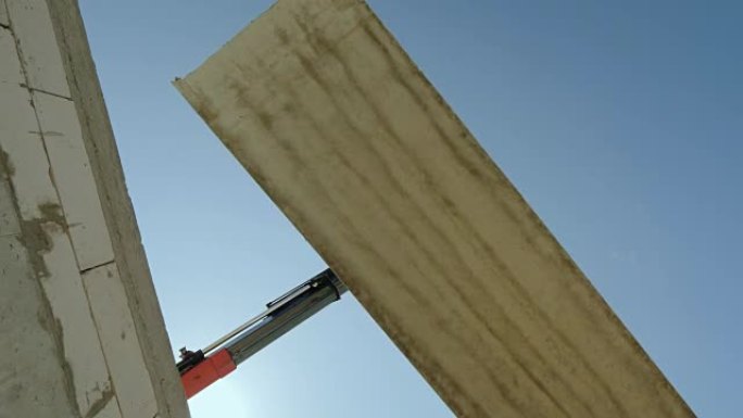 大型钢筋混凝土板悬挂在起重机的吊臂上。危险的职业概念