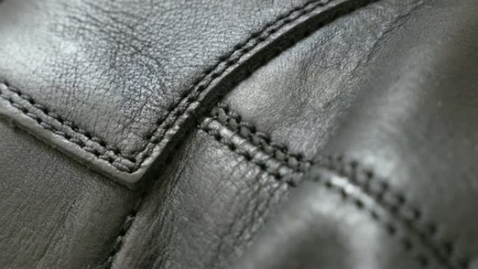 天然深色皮革纹理，缝线特写4K 2160p 30fps UHD倾斜镜头-缓慢倾斜于夹克或射鞋的制造皮