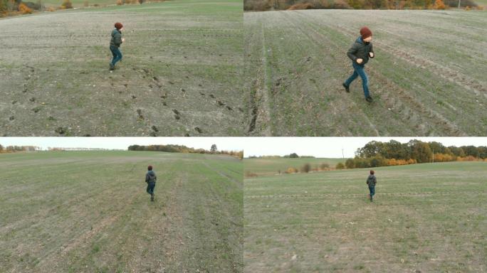 这个孤独的男孩在秋天在一片空旷，耕作的灰色田野中徘徊。黄花鱼正在野外寻找东西。这个男孩正在奔跑和行走