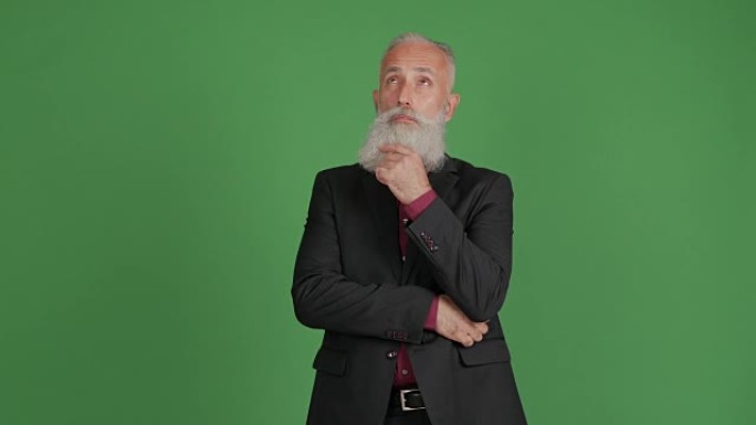 一个成年的大胡子男人在绿色背景上思考并满意他的想法