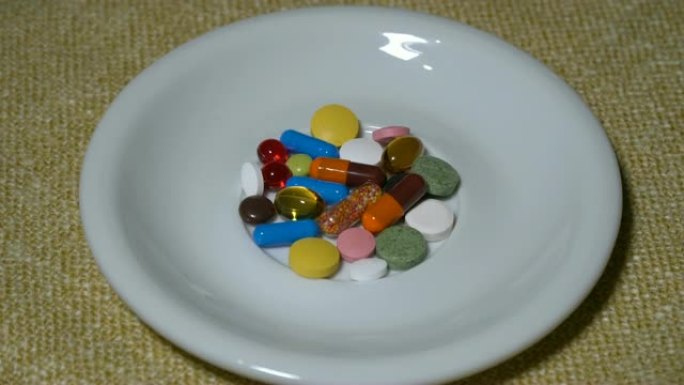 药丸。药物特写。一堆多色药片躺在一个白色的碟子上。生物活性添加剂和维生素。特写。