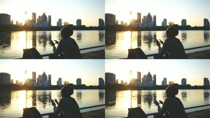 女游客在河边的码头上使用手机。背景模糊，作为首都的建筑物