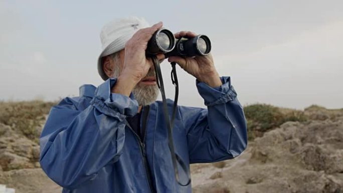 老渔夫用双筒望远镜望向大海