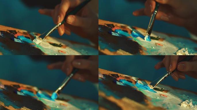 女艺术家用画笔在调色板上混合颜料。女人手握画笔