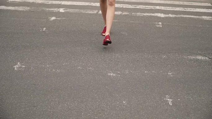 一个穿红鞋的女孩过马路。女人的步态。