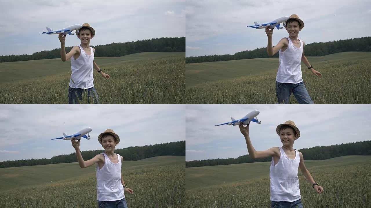 戴着草帽的快乐男孩梦想家手持飞机在户外穿越田野