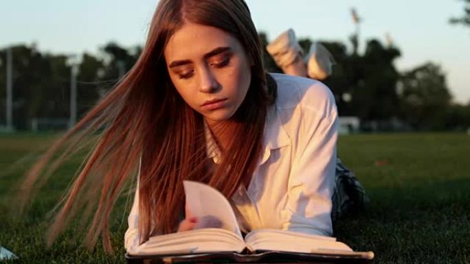 美丽的年轻女子正在公园看书。一个学生和一个女学生。