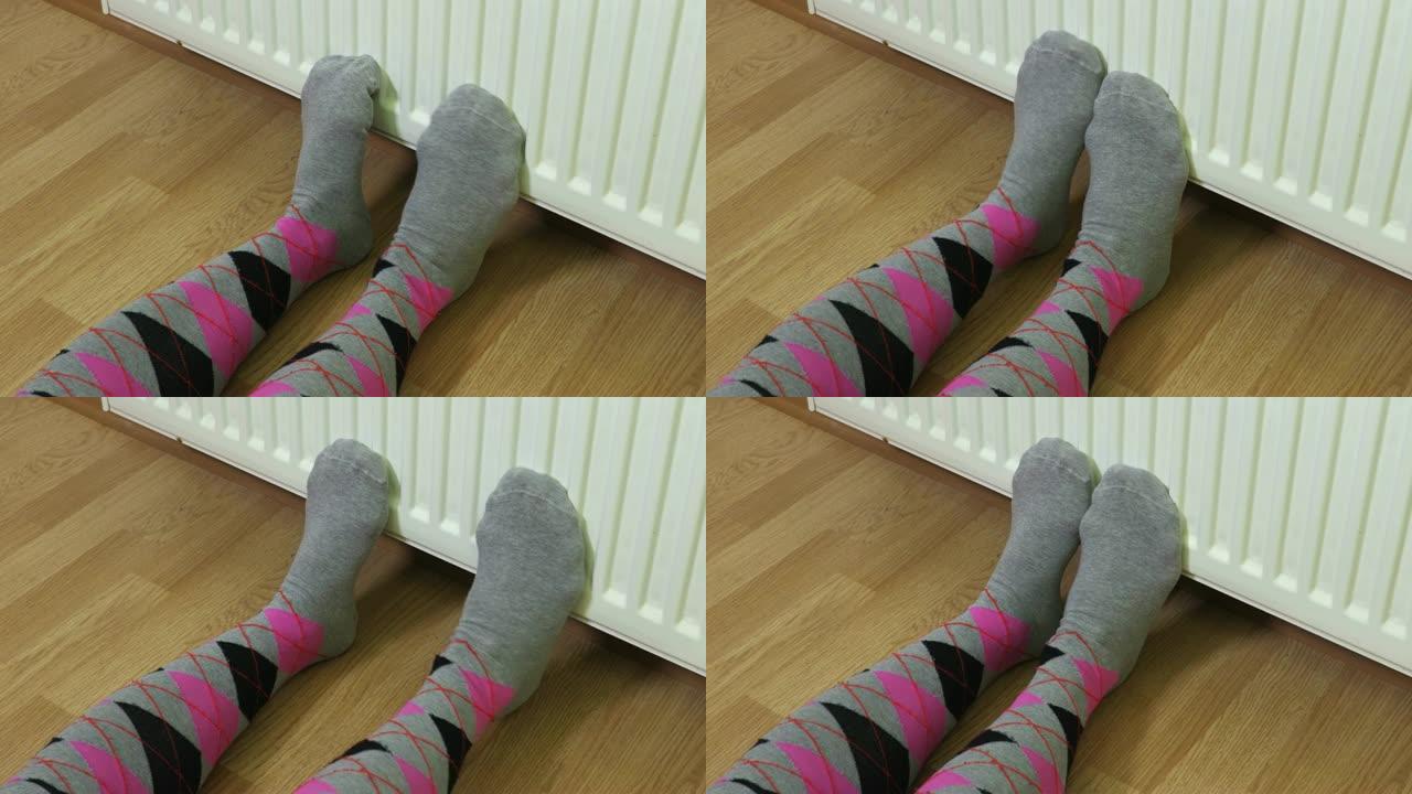 女人在暖气片前穿着彩色袜子保持冷脚