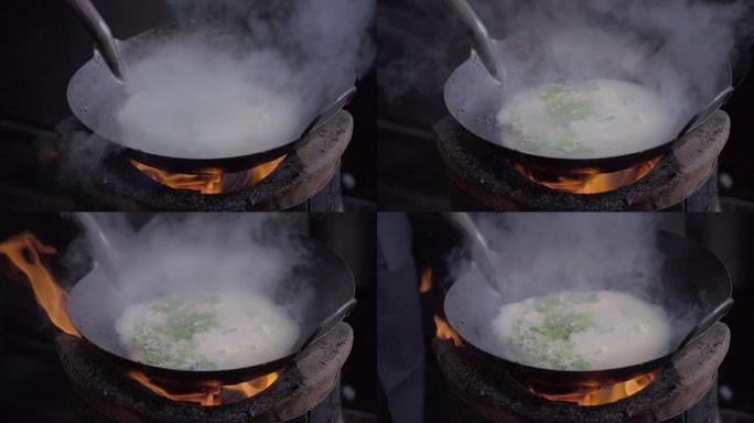 一个男人用炭炉做饭的慢动作镜头。用明火做的炒锅面条。泰国曼谷唐人街的街头美食