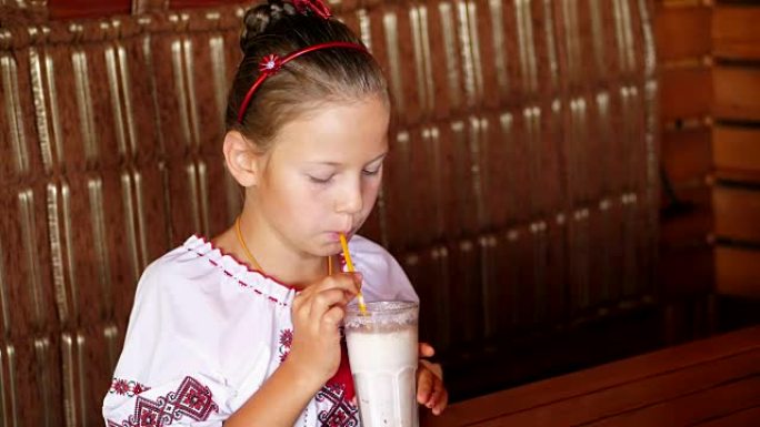 快乐微笑的少女儿童在咖啡馆喝奶昔。她穿着乌克兰民族服装，刺绣，维希万卡