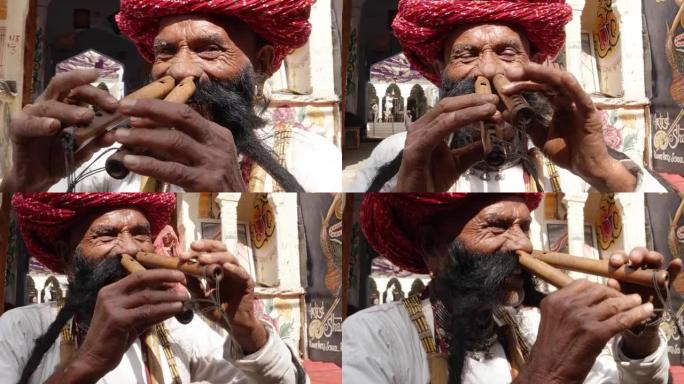 手持CU Rajasthani老年男性在彩绘的庙宇拱门前用鼻子吹笛，大胡子穿着传统服装