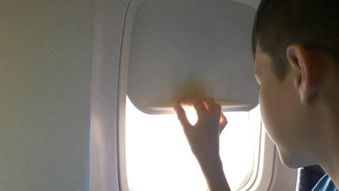 男孩关闭飞机上的舷窗并准备睡觉