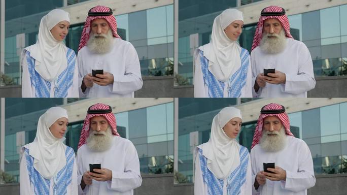 一个留着胡子的阿拉伯老年男子和一个年轻女孩在一个城市的智能手机上写一条信息