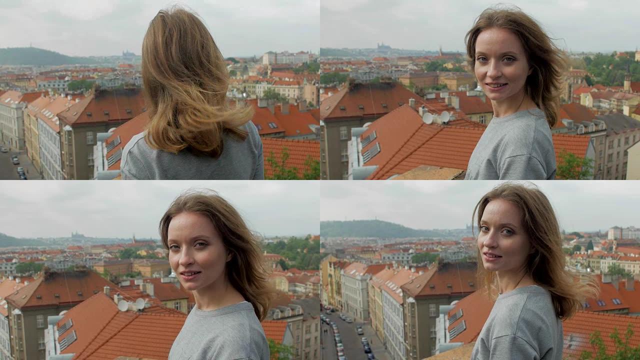 漂亮的金发女孩站在布拉格全景背景下的大风天气中