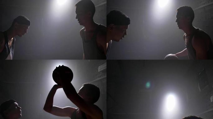 篮球运动员挡住另一名运动员的球，在体育馆里用烟雾和泛光灯打球