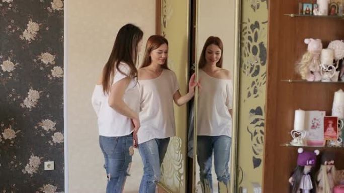 女孩们从壁橱里拿衣服，在镜子前量一量。