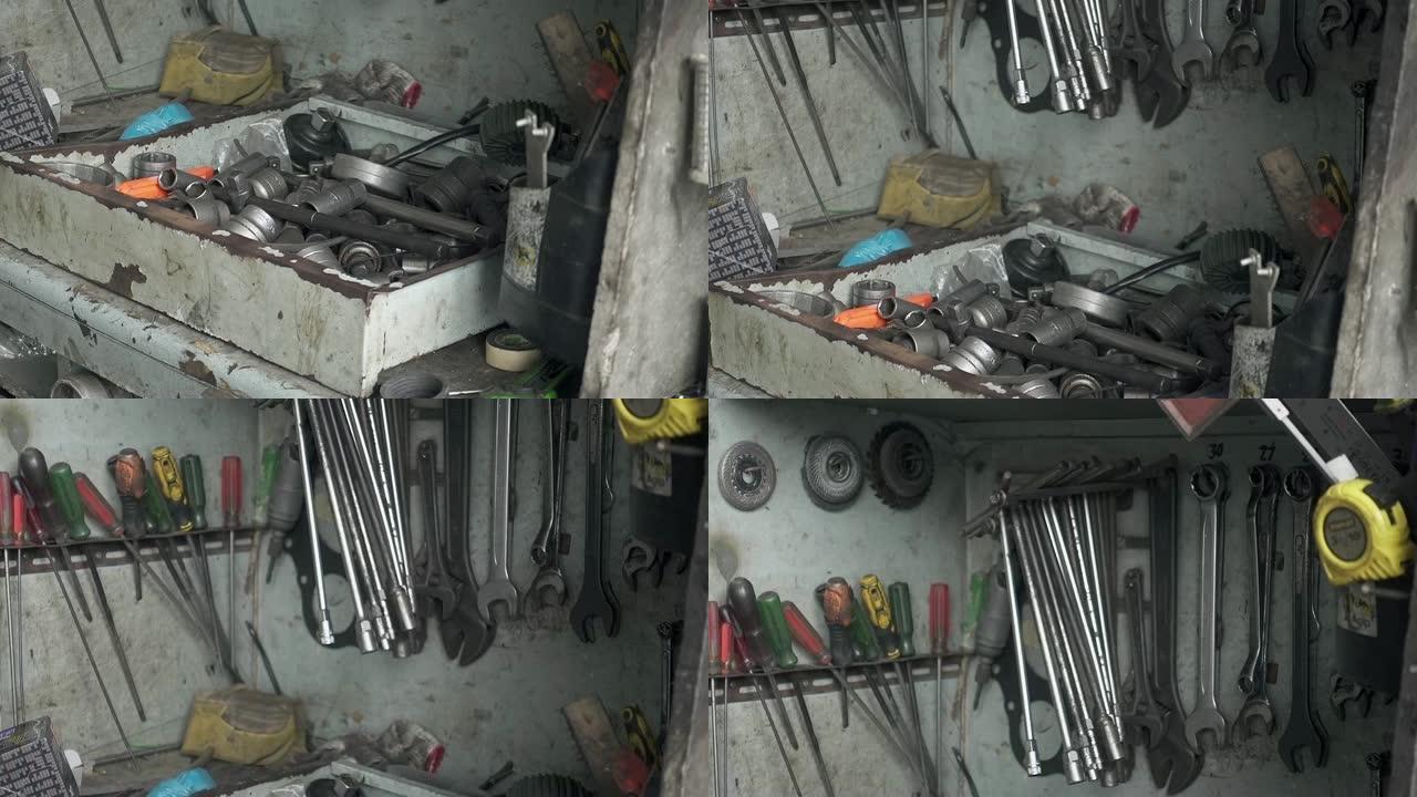 一堆工具放在桌子上，挂在旧肮脏车库的架子上。手持慢动作镜头，29.97fps。