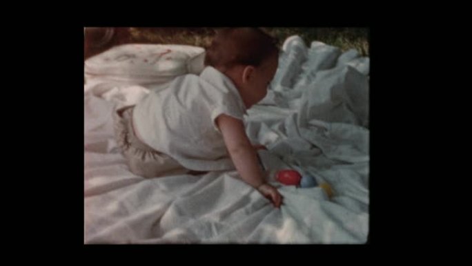 1960快乐的男婴爬着坐在外面的毯子上