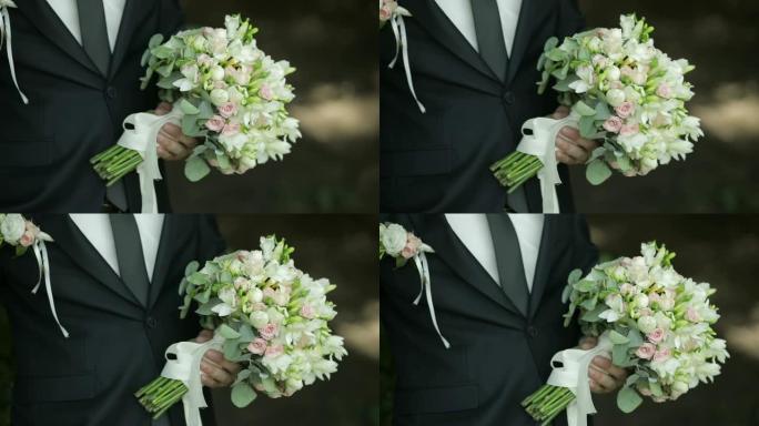 英俊新郎手中的美丽婚礼花束。婚礼当天。慢动作