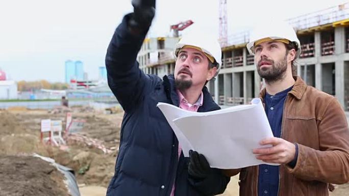 两个工程师正在谈论建筑工程。他们看了两个论文项目