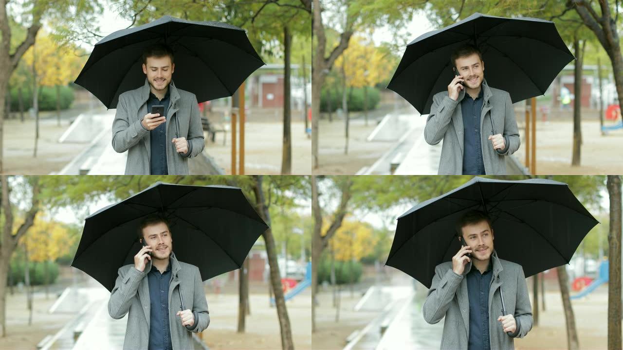 快乐的男人在雨中漫步在电话中