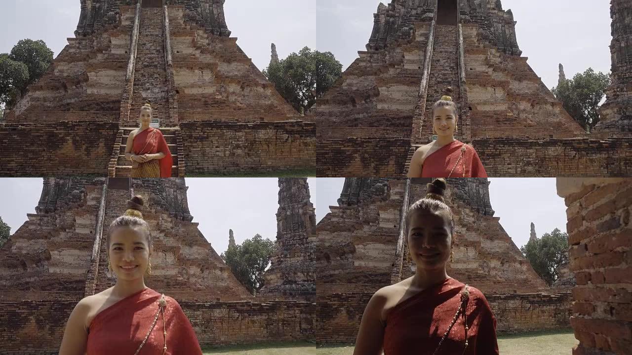 穿着泰国民族礼服的泰国年轻女子在阿育泰的老庙中行走