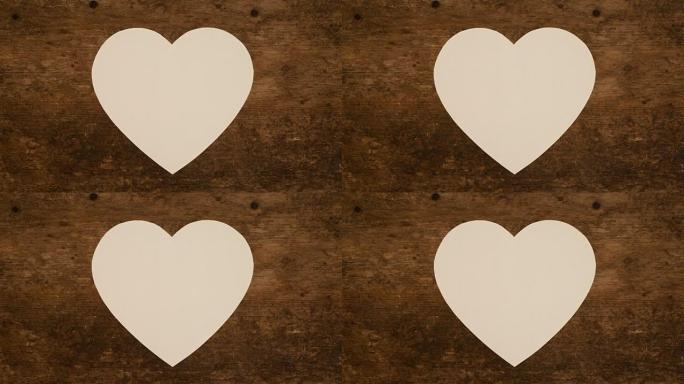 在木制背景上展开和包装心形纸笔记。白纸心的折叠和展开。