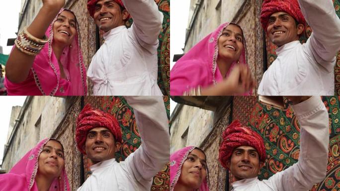 在拉贾斯坦邦的普什卡，穿着传统印度服装的夫妇在手机相机上自拍