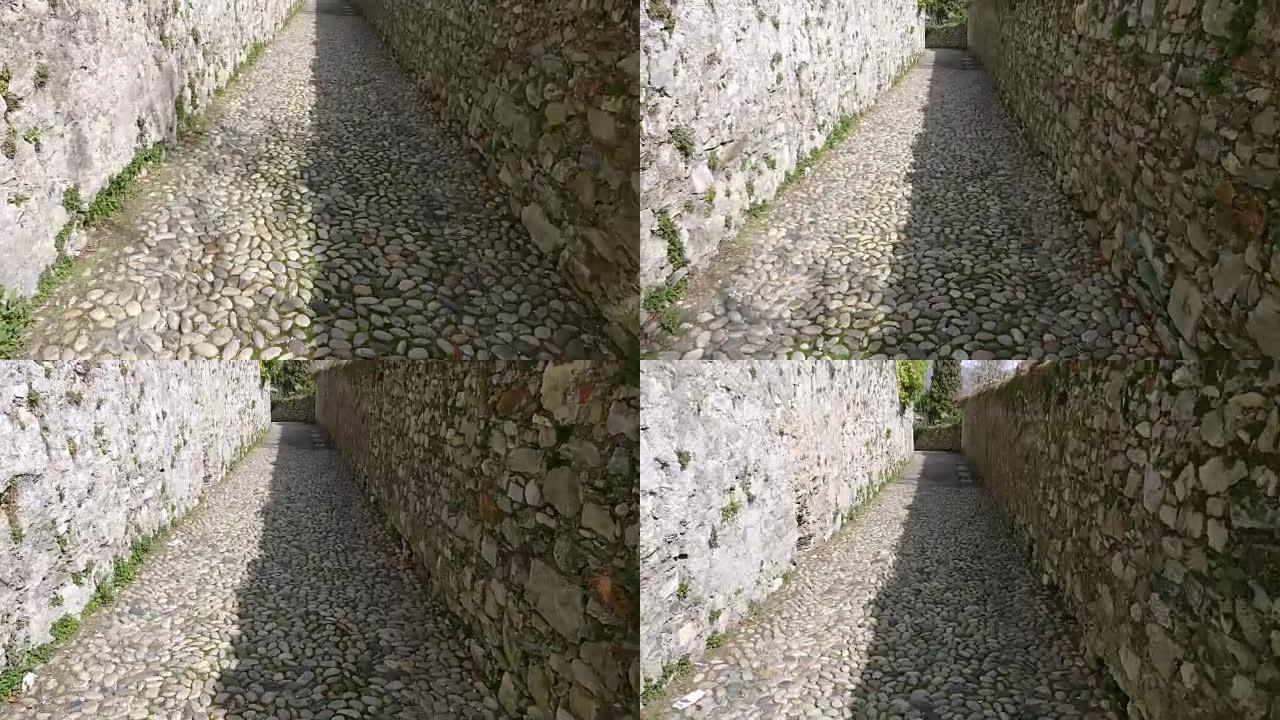 狭窄的鹅卵石路，周围的高墙是用石头砌成的。