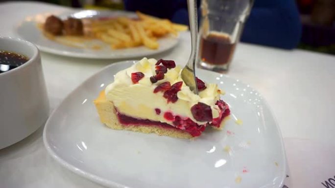 特写，用小红莓叉子吃芝士蛋糕