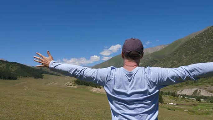 男子站在山上，在青山和高地景观上伸出双臂