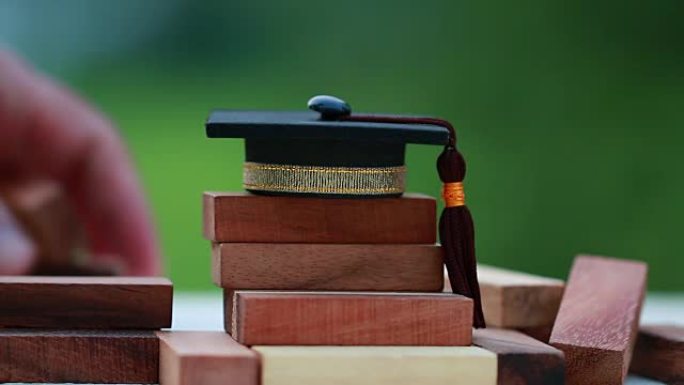 木制方形塔楼上的毕业庆祝帽。信件的空白，如教育、学习计划、毕业生等。出国商务国际教育的构想