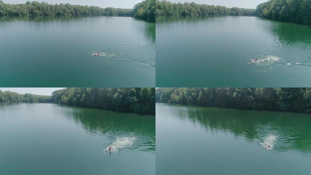 铁人铁人三项运动员男子训练的空中射击。男子在铁人三项比赛的湖泊训练中游泳的无人机射击。健康的生活方式