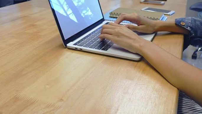 女商人在会议室里使用笔记本电脑。女性手在笔记本电脑键盘上打字的特写。概念博主，写新文章，摄影师。