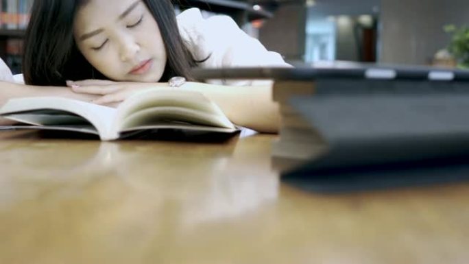 学生亚洲女孩在图书馆看书在桌子上小睡和睡觉。教育理念