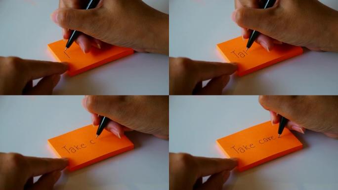 在橙色的便签纸或记事本纸上手写 “保重” 一词。运动4k镜头