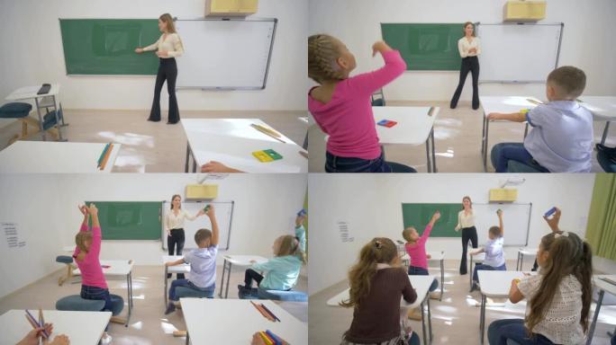 儿童学习，黑板附近的微笑教育者在学校教室的办公桌上为小学习者进行认知课