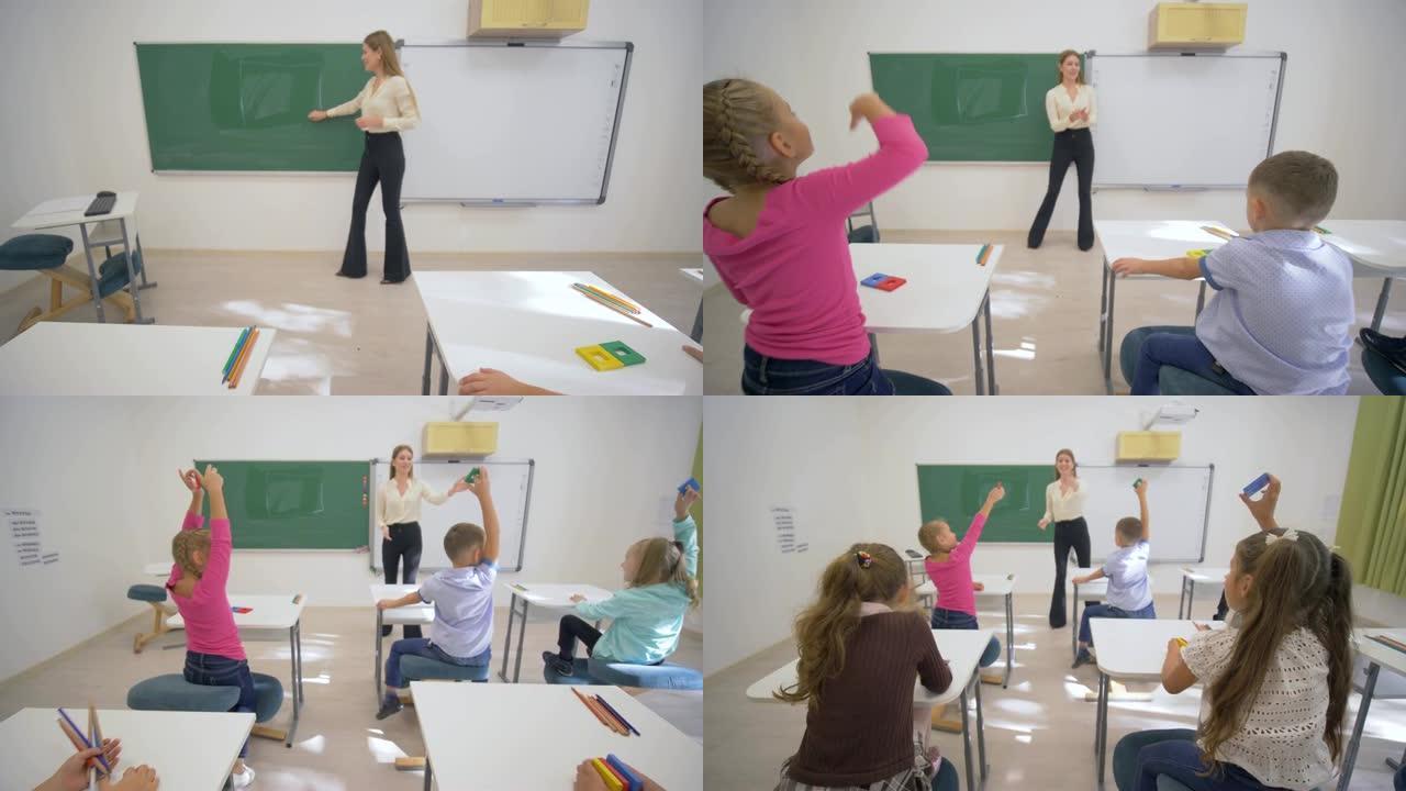 儿童学习，黑板附近的微笑教育者在学校教室的办公桌上为小学习者进行认知课