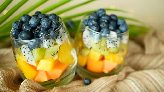 罐装彩色热带混合沙拉。玻璃碗中新鲜的各种生有机浆果和水果。健康素食主义者